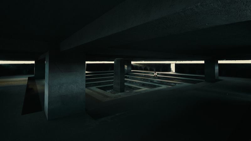 An empty concrete parking deck lit by a single strip of daylight